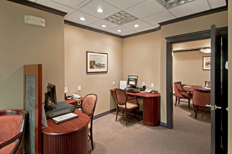 Business center with brown desk, computer stations, and chairs