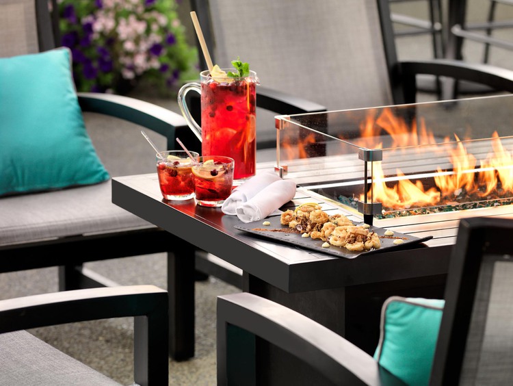 Plate of calamari on table with glass fireplace and pitcher of cocktail