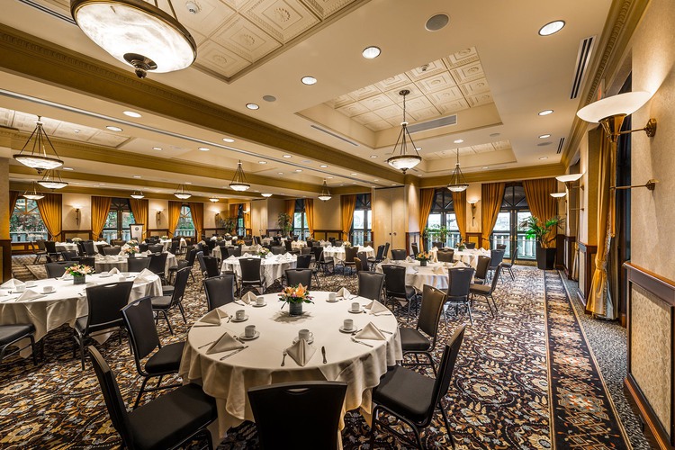 Circular tables with table settings and black chairs in grand ballroom