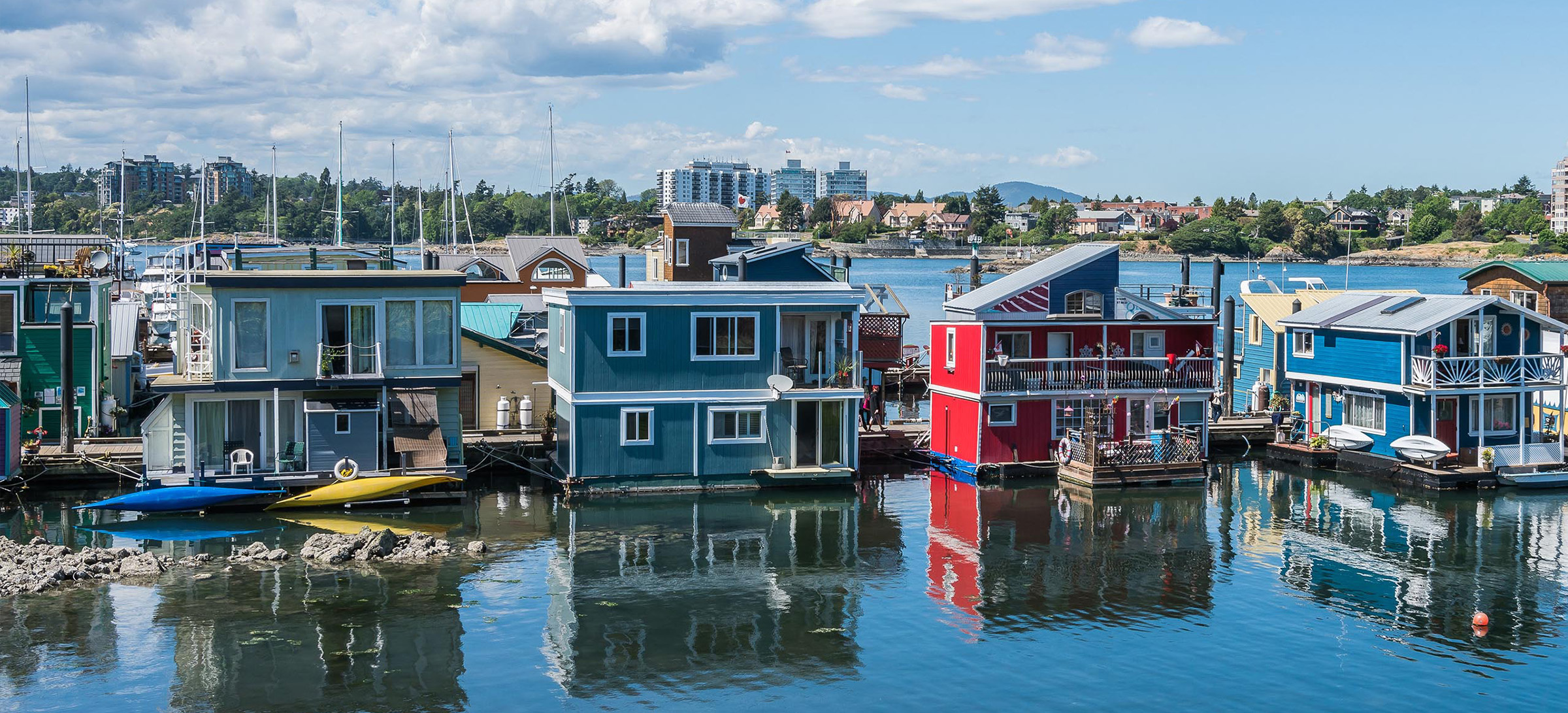 Floating colourful homes on water with city in background